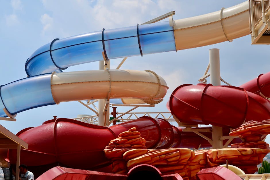 Vibrant water slides in an outdoor amusement park under a clear blue sky.